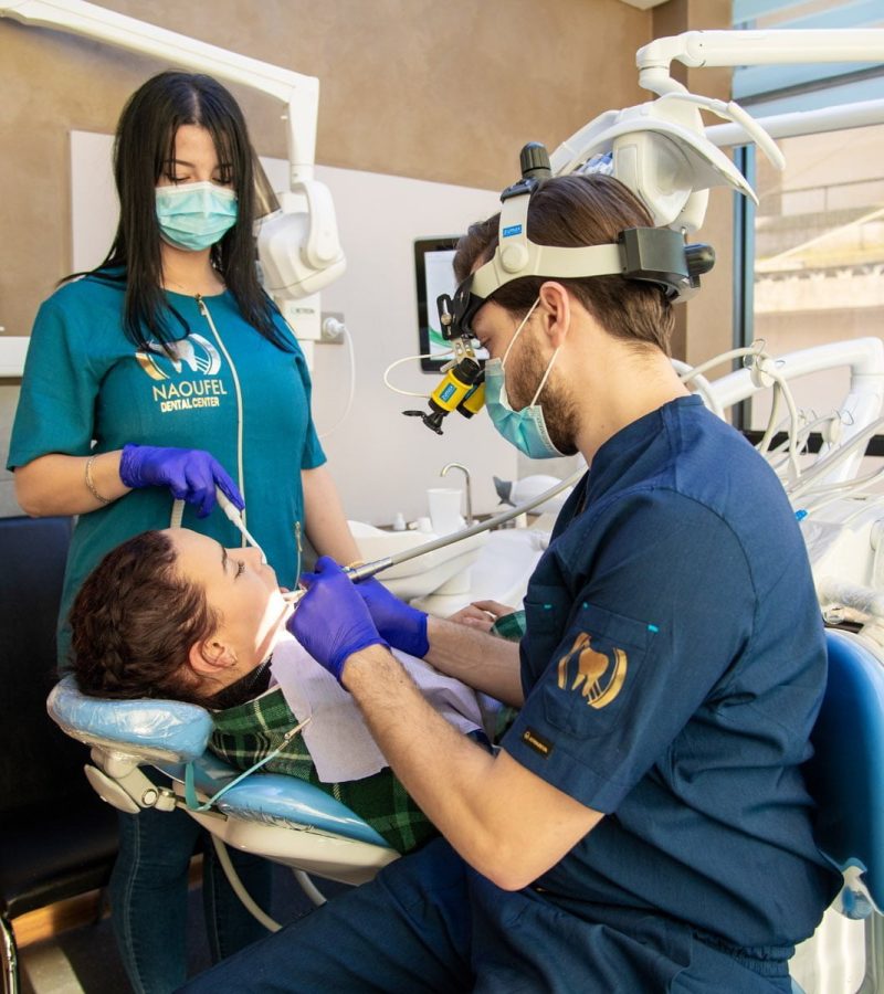 Dr Naoufel entrain d'effectuer une chirurgie dentaire et traitement de la gencive à un patient sur fauteuil dentaire au Cabinet dentaire Naoufel Dental Center à Constantine en Algérie