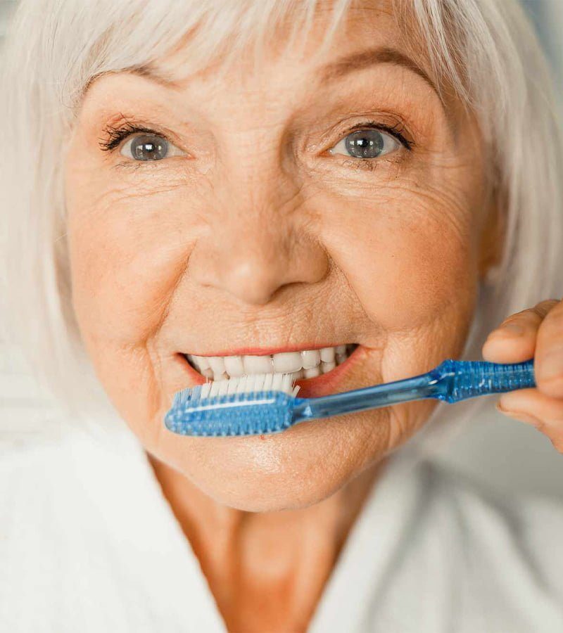 Femme entrain d'entretenir sa prothèse dentaire amovible ou son dentier