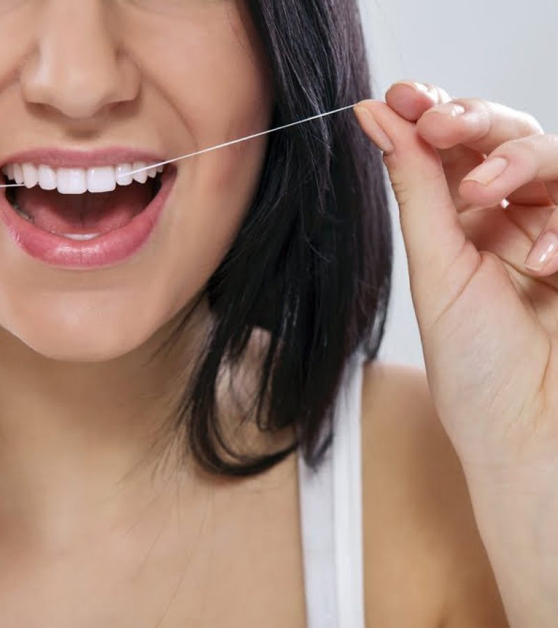 Femme entrain de prendre soin et d'entretenir ses dents avec du fil dentaire