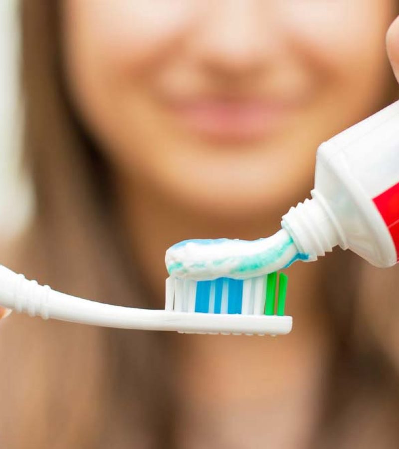 Woman using a toothpaste to clean teeth after teeth whitening, dental implants, dental veneers and hollywood smile, dental care